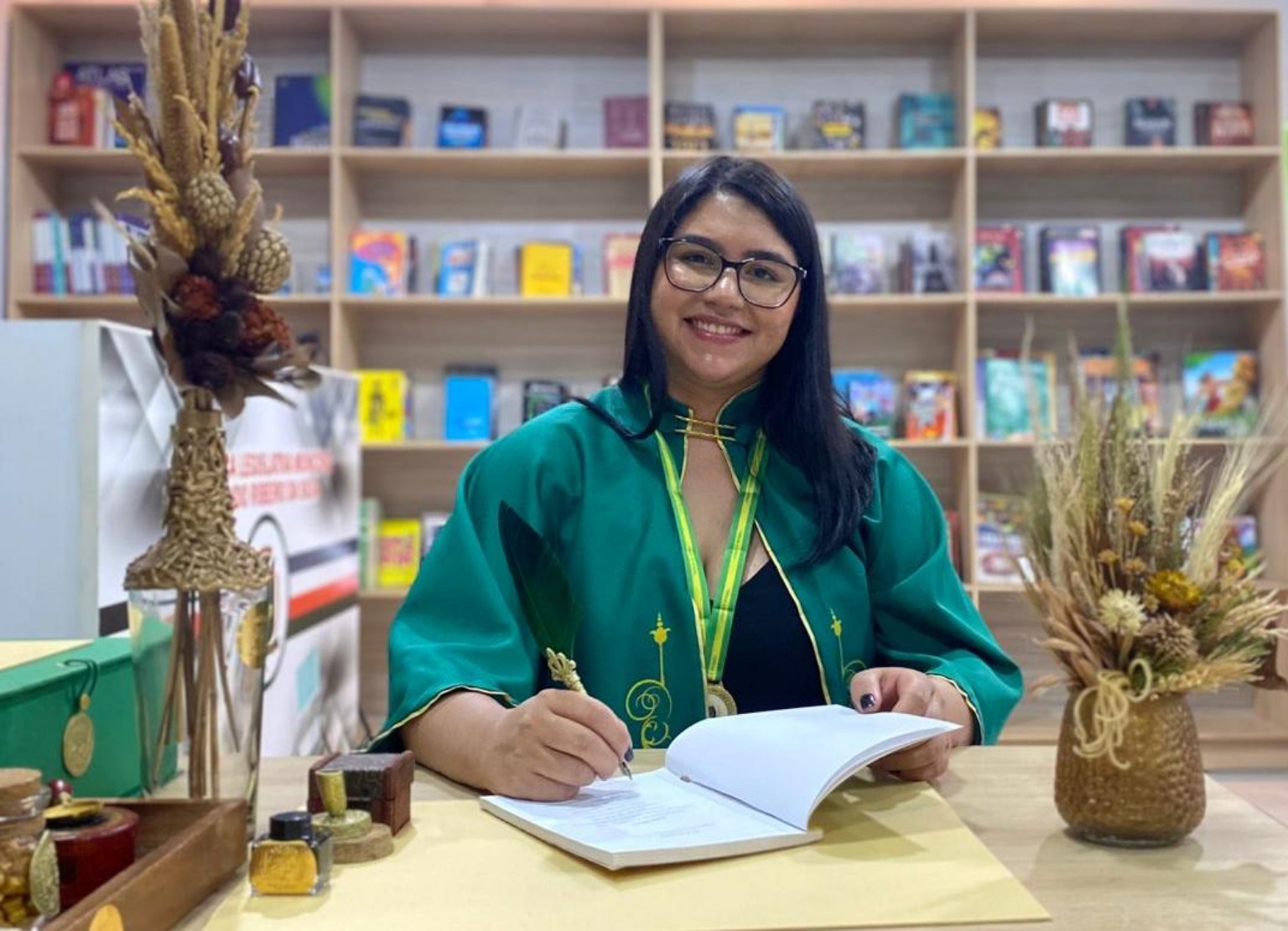 Roziele Mendes escrevendo em um ambiente com livros